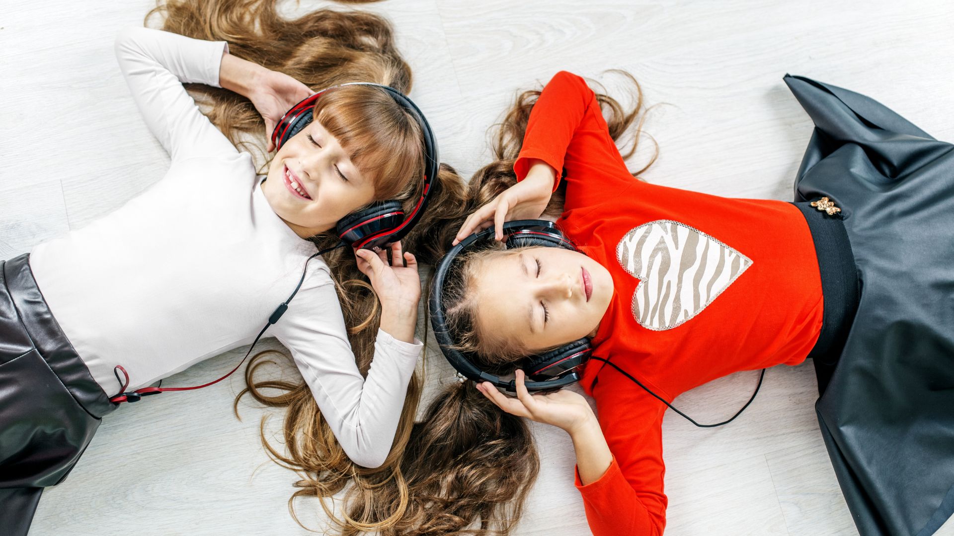 Two Little Girls Laying On The Ground With Headphones On