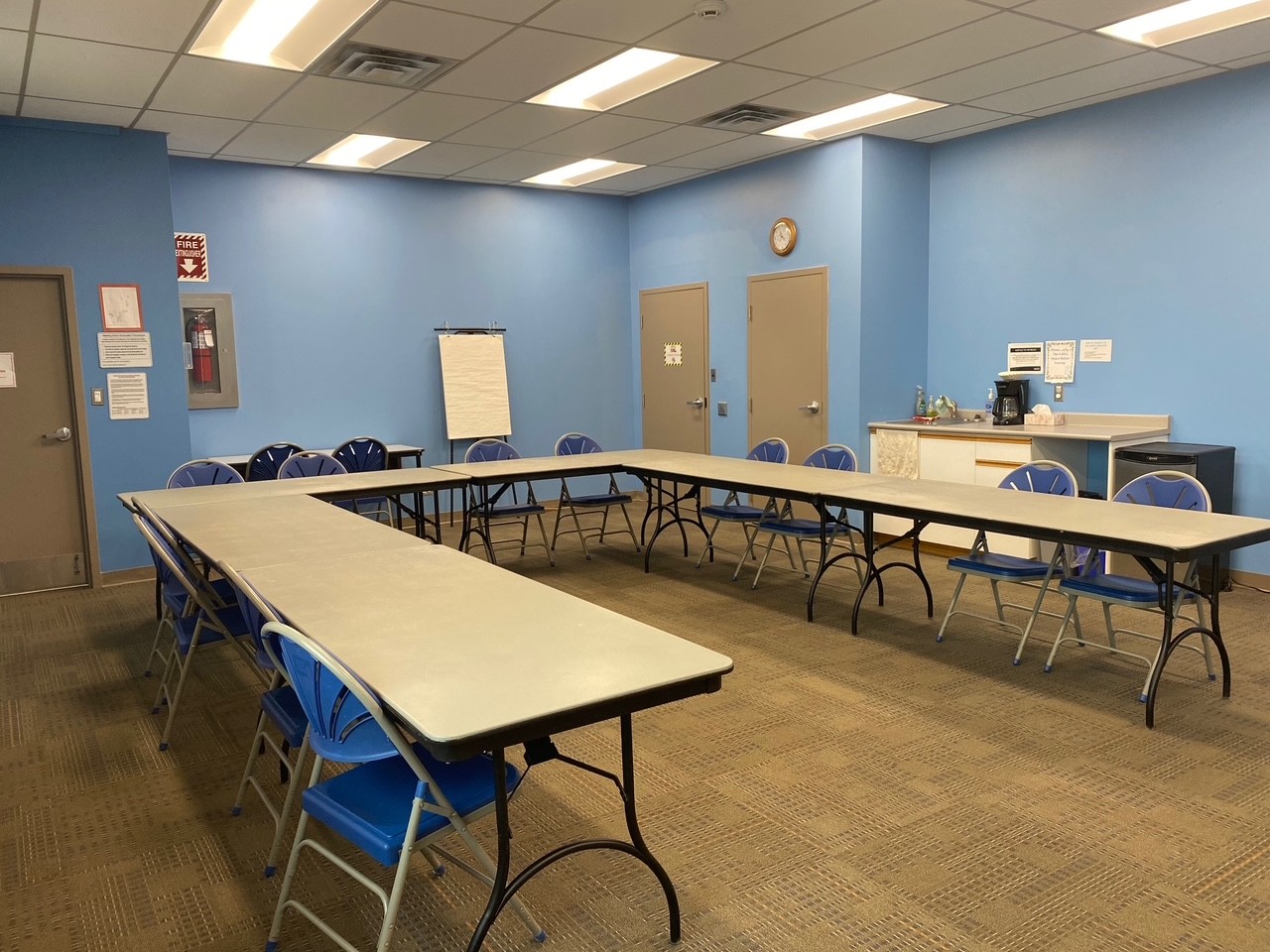 meeting room with blue walls and large U-shaped tables and chairs setup