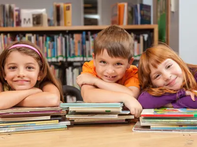 Three kids with their arms cross on top of books
