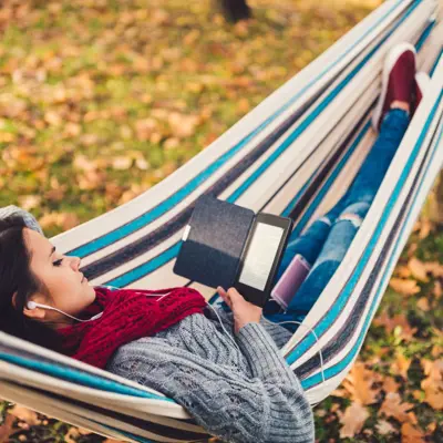 Woman Reading Ebook Outside In A Hammock