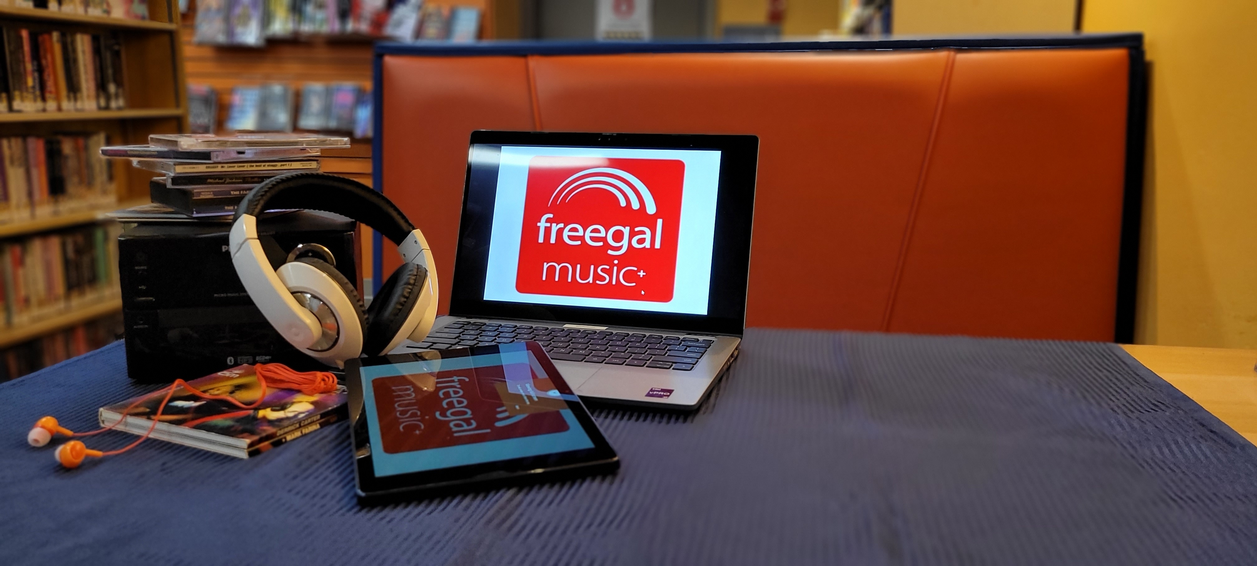 laptop and tablet with cds and headphones on table