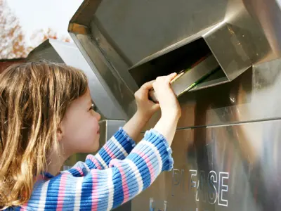 Little Girl Pushing Putting A Book Into The Book Return