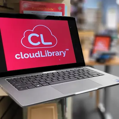 Laptop with CloudLibrary logo on screen on bookshelf