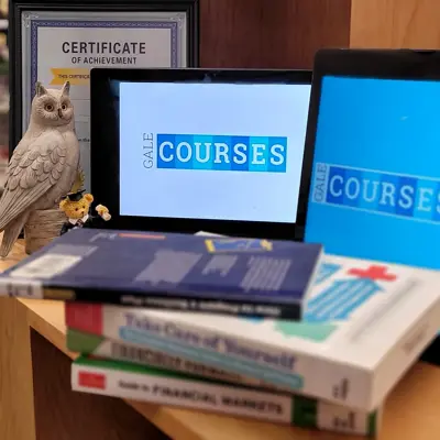 laptop and tablets with owl and teddy bear with graduation cap and self guided learning books